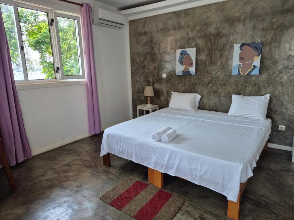 Quarto amplo com cama de casal e arte local no Kriola Hotel